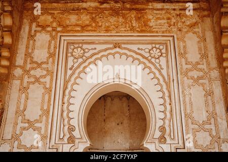 Gros plan à angle bas extérieur d'un ancien bâtiment marocain typique avec murs en pierre ornementaux et porte en forme d'arche Banque D'Images