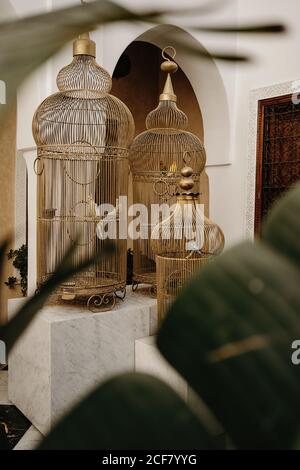 Intérieur élégant de style oriental traditionnel avec cages à oiseaux vintage et des plantes vertes sur sol en marbre dans le hall avec voûté portes et fenêtre ornementale Banque D'Images