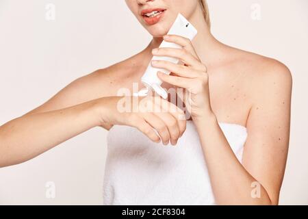 Femme attrayante appliquant de la crème hydratante sur les mains Banque D'Images