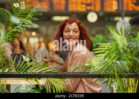 Jeune femme joyeuse travaillant sur un ordinateur portable dans un café Banque D'Images