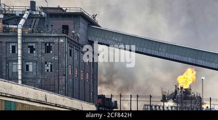 Bâtiments industriels et tuyaux altérés émettant de la fumée et des flammes à usine de cokéfaction Banque D'Images