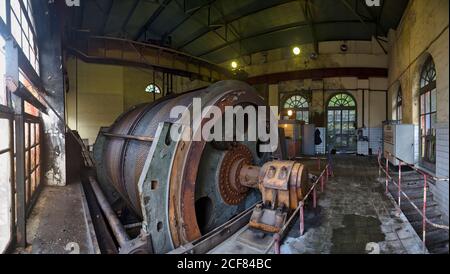 Machine circulaire industrielle rouillée détruite avec mécanisme et réservoirs métalliques localisation dans un atelier industriel délabré et négligé, avec des fenêtres voûtées Banque D'Images