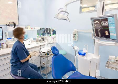 Vue latérale d'un spécialiste en uniforme assis près d'une chaise vide et d'étudier des photos numériques à l'écran Banque D'Images