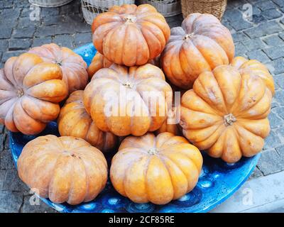 Un bol en céramique bleu avec des citrouilles orange est sur rugueux pavés à l'extérieur Banque D'Images