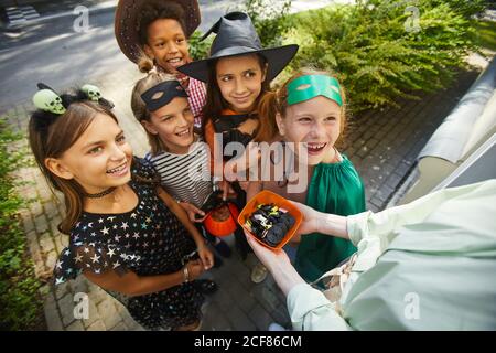 Gros plan sur une femme qui traite des enfants avec des bonbons pendant les vacances d'Halloween à l'extérieur Banque D'Images