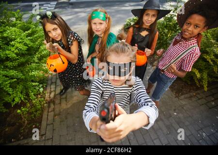 Groupe d'enfants dans les costumes d'Halloween jouant le tour ou le plaisir pendant les vacances, ils se tiennent à l'extérieur et sourient à l'appareil photo Banque D'Images