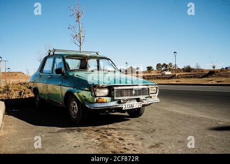 Marrakech, Maroc - 31 décembre 2017 : vieille voiture verte naufragé garée sur le bord de la route dans un environnement rural Banque D'Images