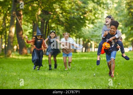 Groupe d'amis heureux jouant ensemble dans le parc pendant Fête d'Halloween Banque D'Images