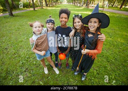 Portrait d'enfants heureux en costumes d'Halloween s'embrassant et sourire à la caméra tout en se tenant dans le parc Banque D'Images
