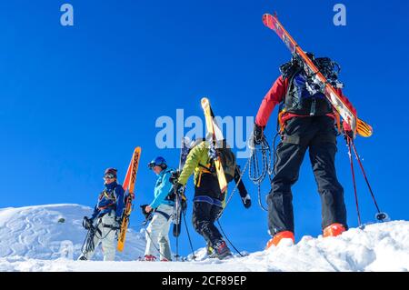 Les freeriders montent sur une colline abrupte lors d'une parfaite journée d'hiver Banque D'Images