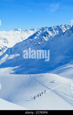 Les freeriders montent sur une colline abrupte lors d'une parfaite journée d'hiver Banque D'Images