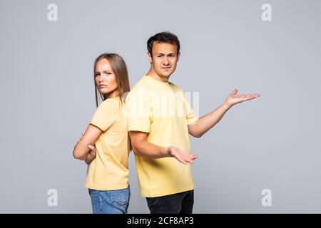 Photo de jeune couple aimant confus des gestes avec les mains sur un mur gris et à la recherche à l'autre. Banque D'Images