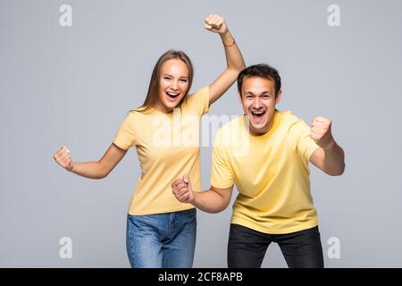 Portrait d'un couple excité ravi impressionné par leur chance dans les poings de tirage de loterie isolés sur fond gris Banque D'Images