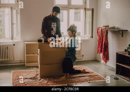 Hipster couple déballer les boîtes tout en se tenant pieds nus dans la lumière chambre Banque D'Images