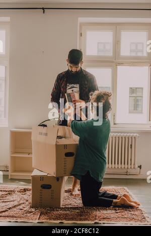 Hipster couple déballer les boîtes tout en se tenant pieds nus dans la lumière chambre Banque D'Images