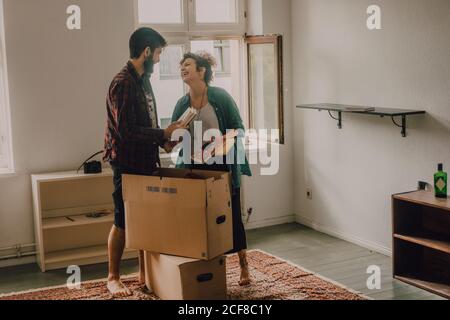 Hipster couple déballer les boîtes tout en se tenant pieds nus dans la lumière chambre Banque D'Images