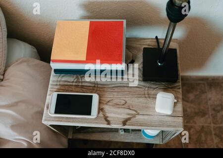 Des PC portables et smartphones avec une véritable connexion sans fil écouteurs et lampe sur table de chevet en bois dans la chambre confortable d'appartement moderne Banque D'Images