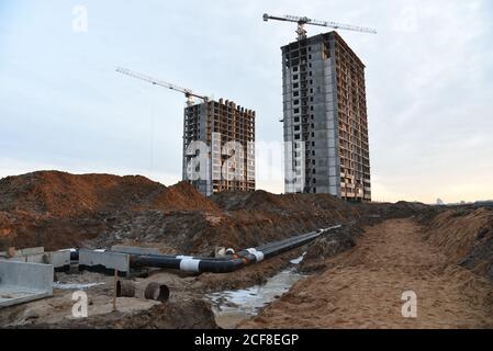 Pose de tuyaux d'égout pluvial souterrains sur le chantier de construction. Installation de conduites d'eau et d'égouts sanitaires sur les grues de fond et les grues bleues Banque D'Images