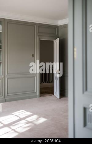 Intérieur de la maison lumineuse avec mur lambrissé et blanc porte ouverte montrant des escaliers de conception minimaliste Banque D'Images