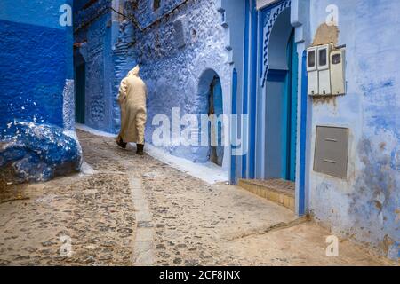 Homme vêtu de promenades traditionnelles dans la célèbre ville bleue de Chefchaouen, au Maroc. Banque D'Images