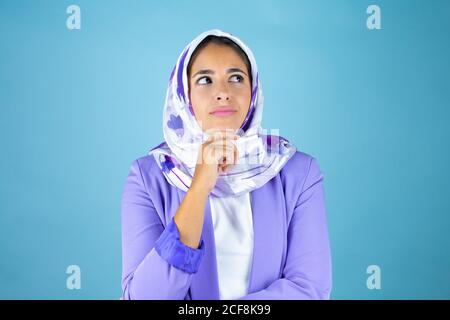 Jeune belle femme arabe portant le hijab islamique sur un bleu isolé arrière-plan de la pensée et de regarder sur le côté Banque D'Images