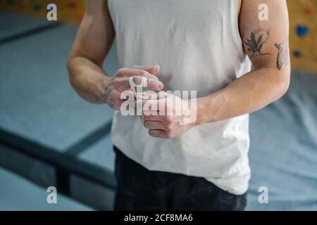 Par dessus l'athlète anonyme masculin en tenue active debout et de toucher les doigts dans la poudre de talc dans la salle de gym Banque D'Images