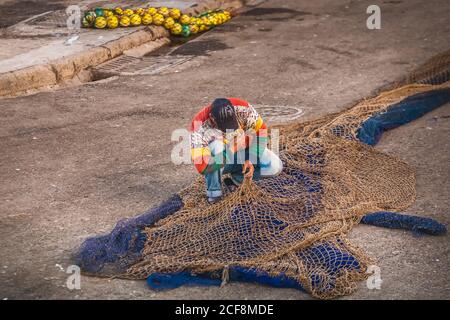 Le pêcheur fixe le filet au port d'Essaouira, au Maroc. Banque D'Images