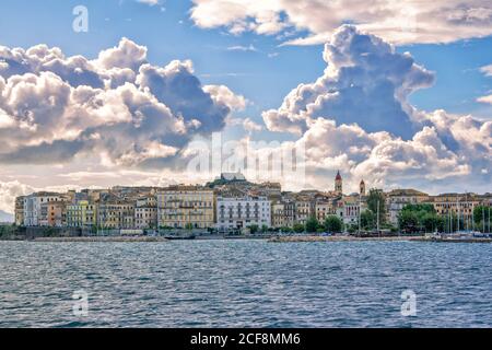 Île de Corfou/Grèce- 7 mai 2019: Kerkyra paysage urbain - baie de mer avec eau turquoise calme, vieilles maisons colorées, ciel bleu avec des nuages blancs et des collines sur Banque D'Images