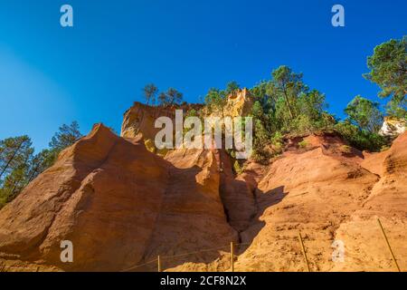 L'Ocher chemin le Sentier des Acres à travers les falaises rouges de Roussillon les Acres, un parc naturel du Vaucluse, Provence, France. Banque D'Images