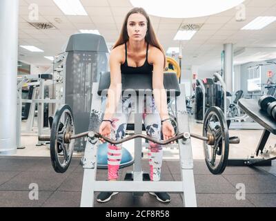 Femme forte faisant des boucles biceps sur barbell sur le banc dans la salle de gym Banque D'Images