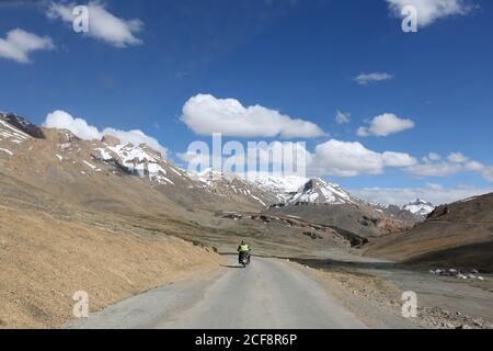 Homme en vélo avec toile de fond enneigée de montagne, Leh, Ladakh, Jammu et Cachemire Banque D'Images