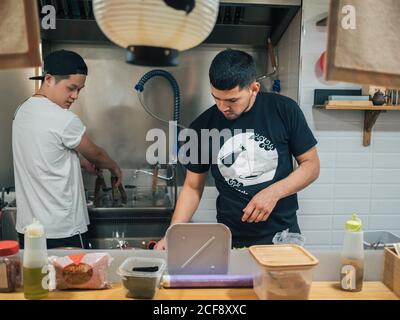 De jeunes hommes multiraciaux cuisent et servent des plats japonais Bistrot asiatique Banque D'Images