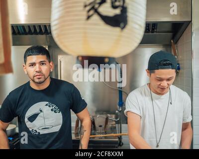 De jeunes hommes multiraciaux cuisent et servent des plats japonais Bistrot asiatique Banque D'Images