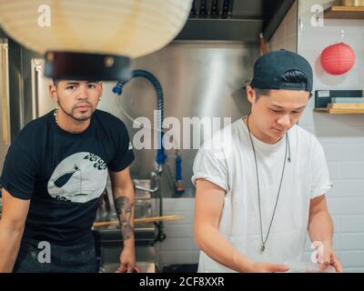 De jeunes hommes multiraciaux cuisent et servent des plats japonais Bistrot asiatique Banque D'Images