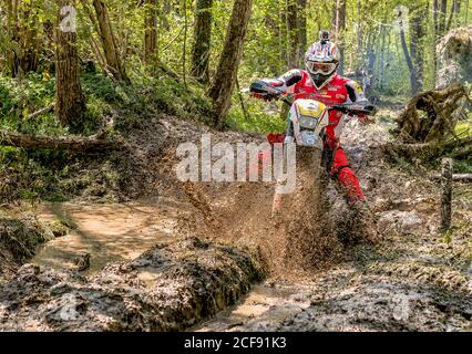 Biandronno, Lombardie, Italie - 22 avril 2018: Motocross motard éclaboussant la boue sur terrain humide et boueux. Concours ouverts en motocross. Banque D'Images