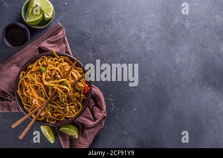 Pâtes végétariennes asiatiques, nouilles udon faites maison avec champignons shiitake sautés, sésame et légumes, sauce soja et citron vert, copie de fond gris foncé Banque D'Images