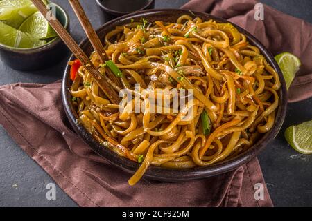 Pâtes végétariennes asiatiques, nouilles udon faites maison avec champignons shiitake sautés, sésame et légumes, sauce soja et citron vert, copie de fond gris foncé Banque D'Images