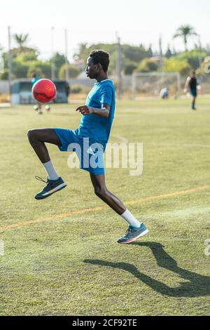 Ballon de football ethnique adolescent juglant Banque D'Images