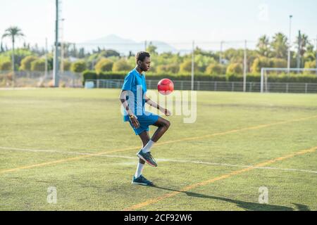 Ballon de football ethnique adolescent juglant Banque D'Images