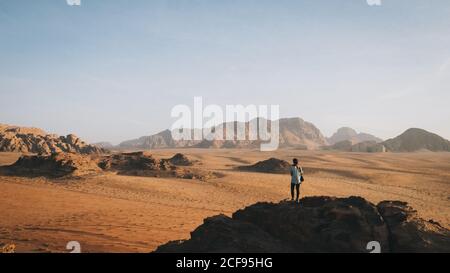 Femme se tient au sommet du rocher en regardant Wadi Rhum Banque D'Images