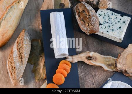 De dessus délicieux différents types de fromage blanc et croustillant pain frais avec des morceaux de bois sur une table rustique Banque D'Images