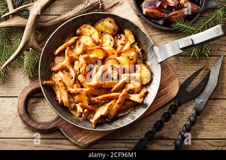 Portion de lanières épicées de viande de venaison sauvage avec frit des quartiers de pommes de terre croustillants dans une taverne rustique en haut vue sur le bas avec bois de cerf Banque D'Images