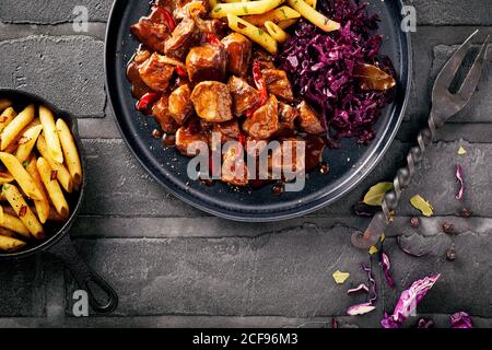 Assiette de délicieux ragoût allemand ou ragoût avec des dés de maigre viande assaisonnée de piments et servie avec des pommes de terre frites dans une vue descendante Banque D'Images