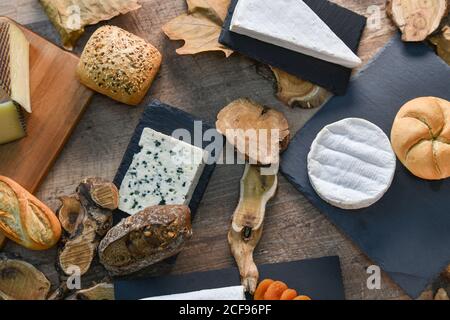 De dessus délicieux différents types de fromage blanc et croustillant pain frais avec des morceaux de bois sur une table rustique Banque D'Images