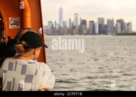 New York City, États-Unis - 7 octobre 2019 : deux personnes photographiées de derrière, en regardant depuis le ferry Staten Island en direction de Manhattan. La ligne d'horizon de manha Banque D'Images