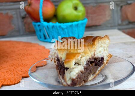 la cuisine maison, sur une plaque de verre se trouve un morceau de gâteau farci de confiture de pomme avec des cerises, des noix et des pommes dans un panier Banque D'Images