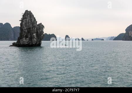 Un pêcheur dans son bateau avec les karsts de calcaire dans le fond de Hạ long Bay, Vietnam, Asie Banque D'Images