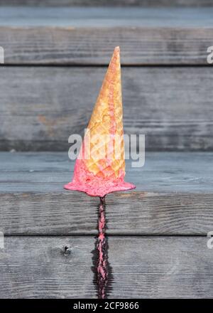 Du dessus de la glace rose dans le cône de cachets a chuté sur table en bois avec traces de fusion Banque D'Images