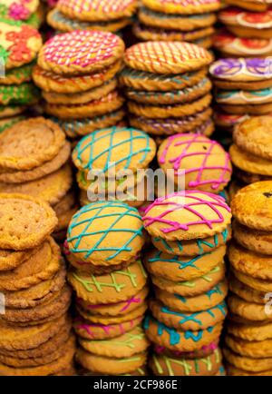 De plus en plus gros plan de biscuits sucrés empilés décorés de couleurs vives givrage sur la table Banque D'Images
