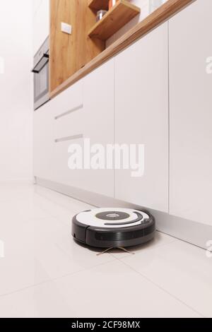 Aspirateur robotique travaillant sur un sol de cuisine Banque D'Images